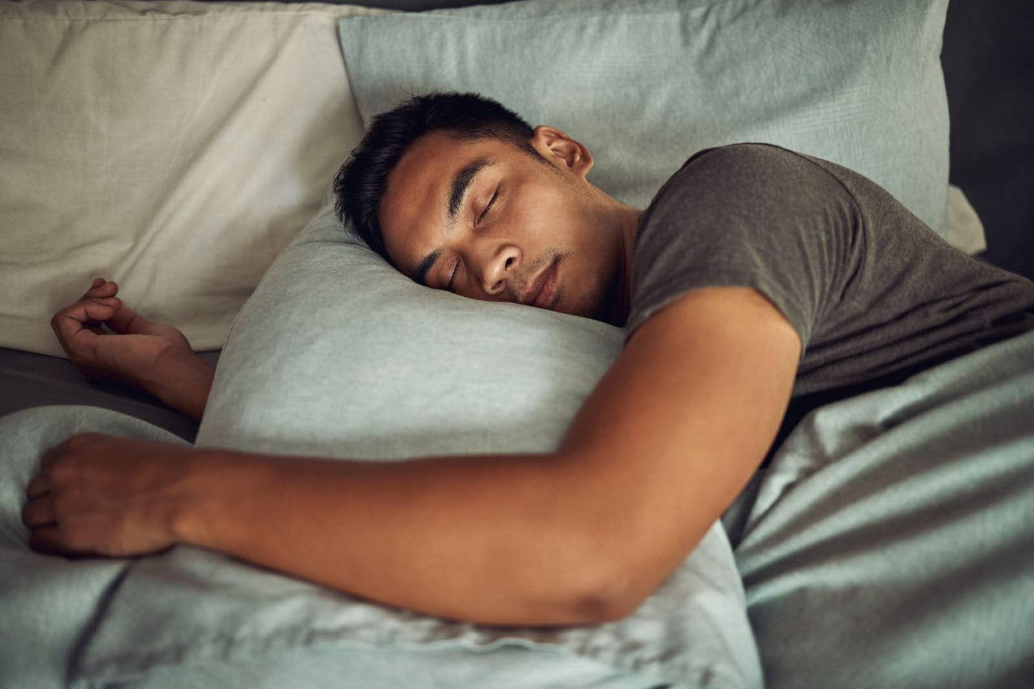 A man is sleeping soundly in bed resting his head on a pillow